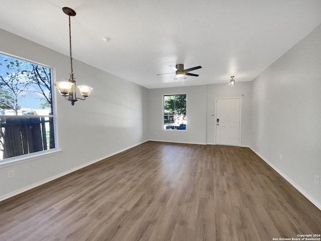 spare room featuring dark wood-type flooring and ceiling fan with notable chandelier