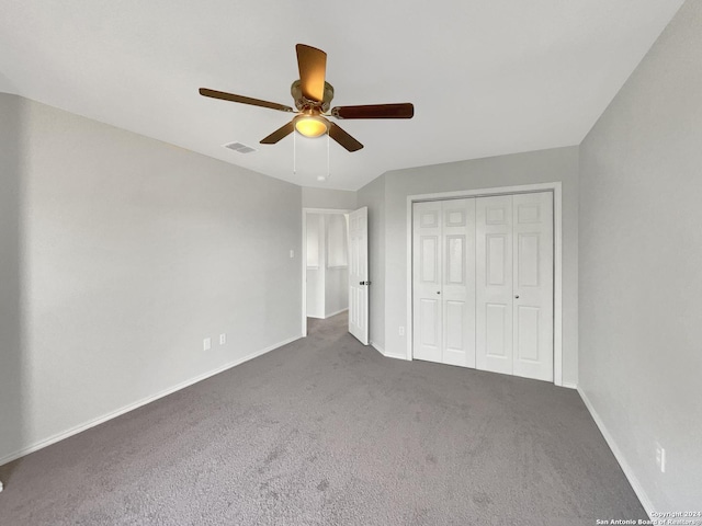 unfurnished bedroom with dark colored carpet, a closet, and ceiling fan