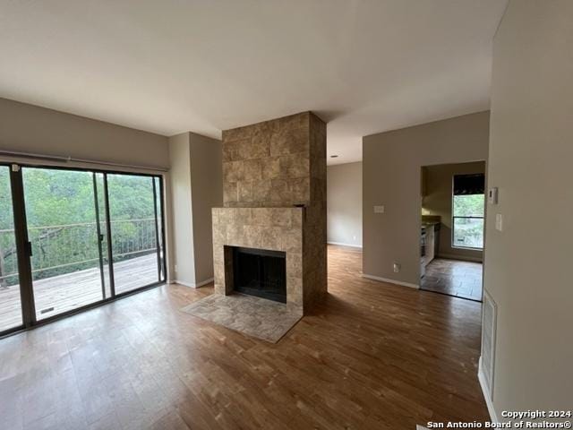 unfurnished living room featuring a tile fireplace, hardwood / wood-style flooring, and a wealth of natural light