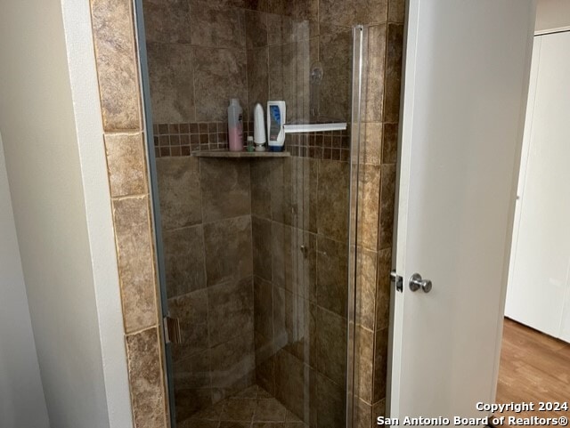 bathroom with hardwood / wood-style flooring and walk in shower