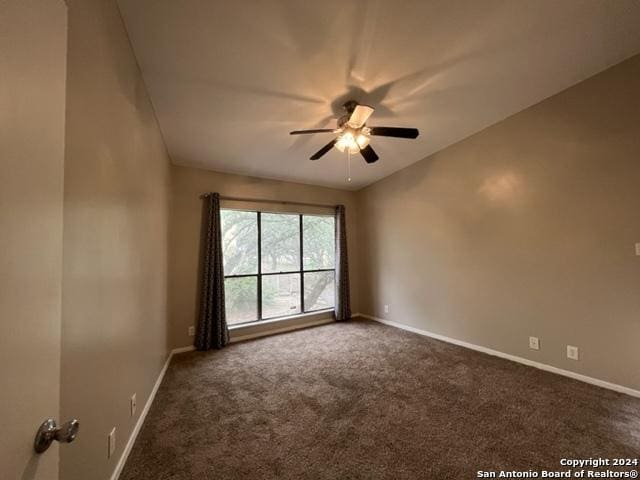 empty room with dark colored carpet and ceiling fan