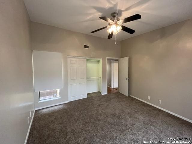 unfurnished bedroom with dark colored carpet, a closet, and ceiling fan