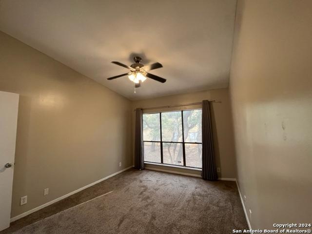 unfurnished room with ceiling fan, dark carpet, and vaulted ceiling