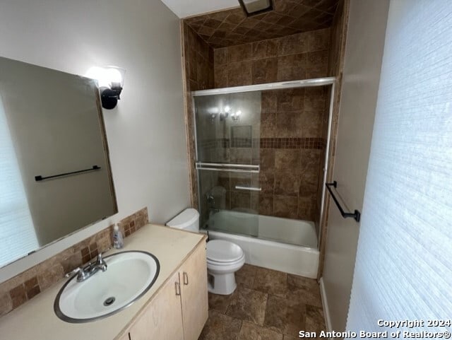 full bathroom featuring vanity, toilet, and bath / shower combo with glass door