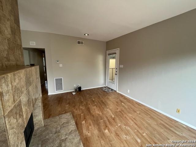 unfurnished room with a tile fireplace and hardwood / wood-style flooring