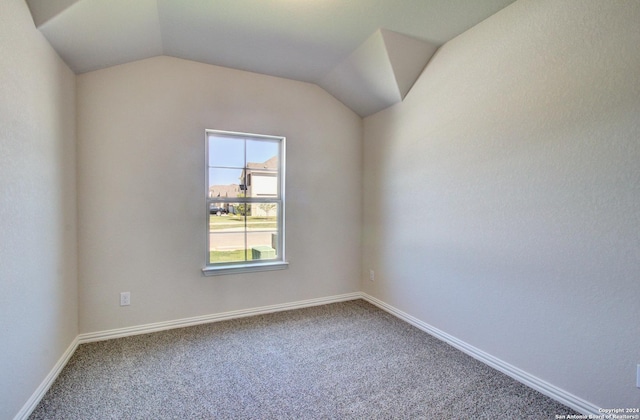 carpeted spare room featuring vaulted ceiling