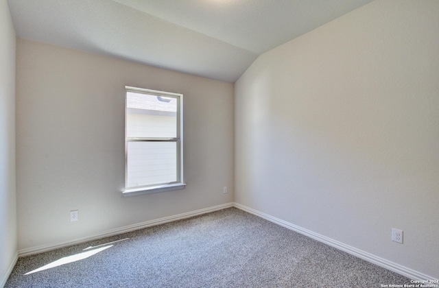 carpeted spare room featuring vaulted ceiling