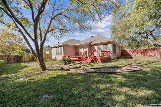 rear view of property featuring a lawn and a wooden deck