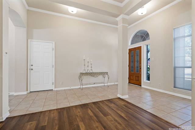 entryway featuring light wood-type flooring, crown molding, and a high ceiling