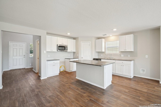 kitchen with a wealth of natural light, dark hardwood / wood-style flooring, white cabinets, and stainless steel appliances