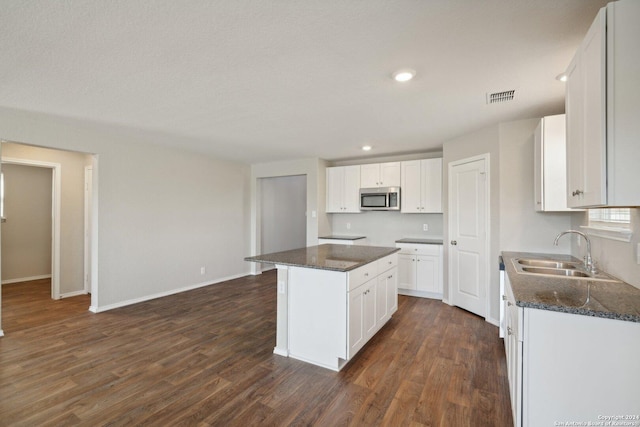 kitchen with white cabinets, a kitchen island, dark hardwood / wood-style flooring, and sink