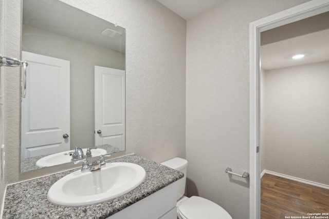 bathroom with hardwood / wood-style floors, vanity, and toilet