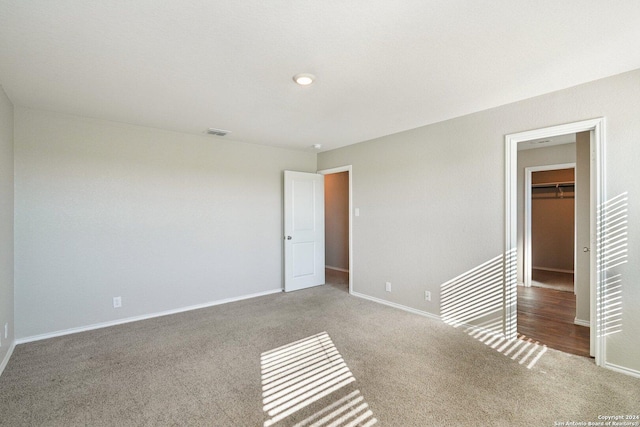 unfurnished bedroom with carpet, a walk in closet, and a closet