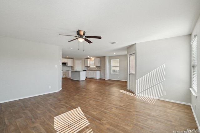 unfurnished living room with hardwood / wood-style flooring, ceiling fan, and a healthy amount of sunlight