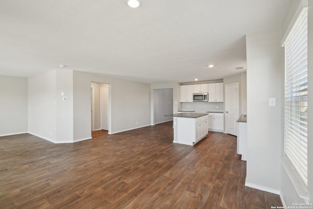 kitchen with white cabinets, a center island, and dark wood-type flooring