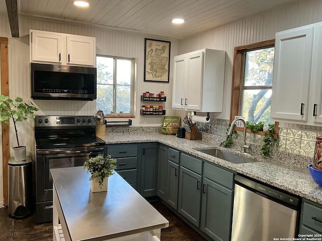 kitchen with white cabinets, appliances with stainless steel finishes, dark hardwood / wood-style floors, and sink