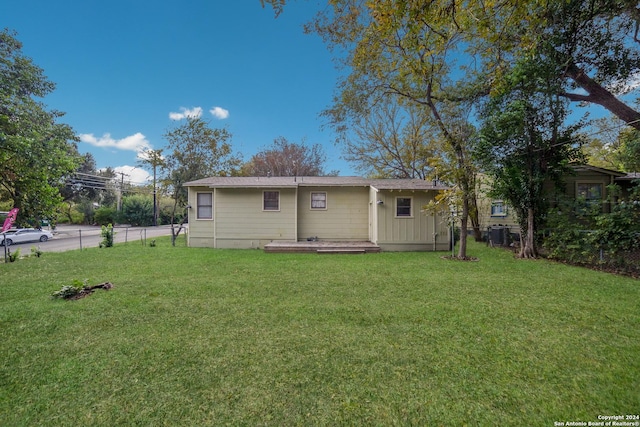 back of house with cooling unit and a yard