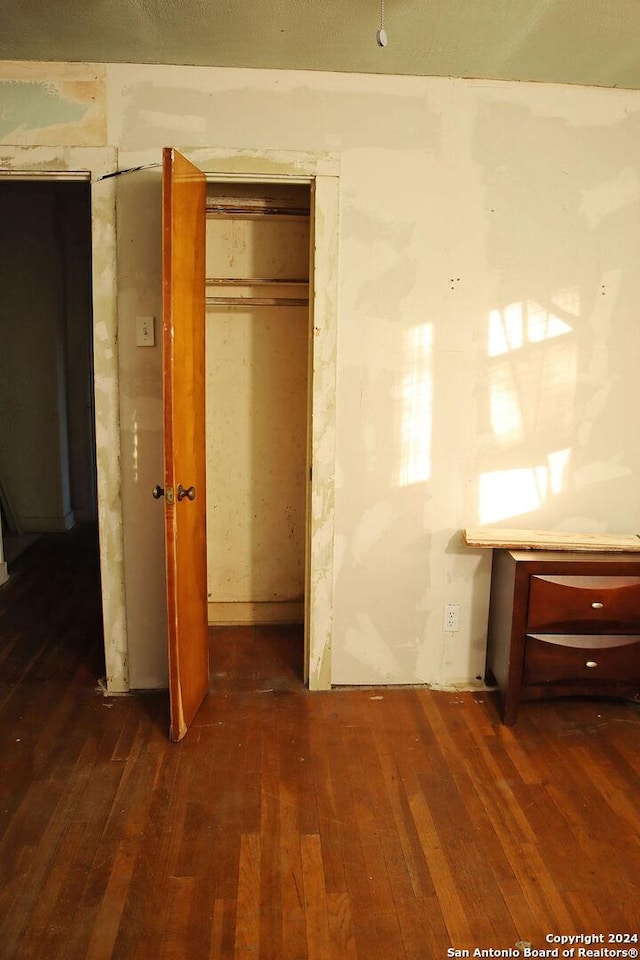 unfurnished bedroom with dark wood-type flooring and a closet