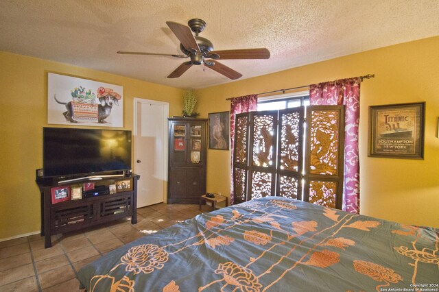 bedroom featuring ceiling fan, light tile patterned floors, and a textured ceiling