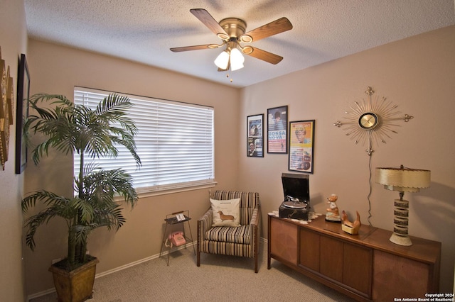 sitting room with a textured ceiling, ceiling fan, and light carpet