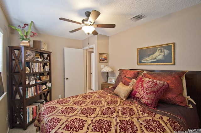 carpeted bedroom with ceiling fan and a textured ceiling