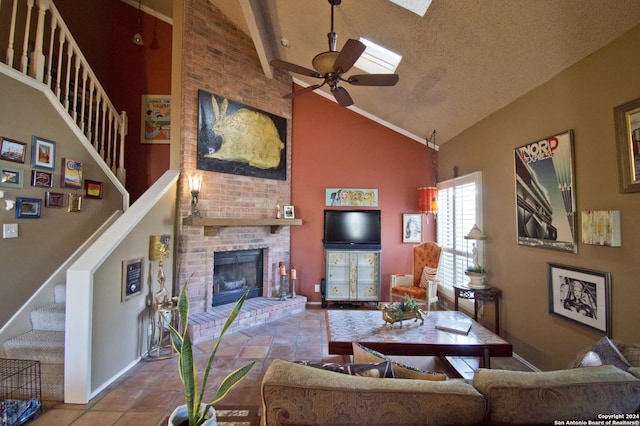 living room with a textured ceiling, ceiling fan, high vaulted ceiling, a fireplace, and light tile patterned flooring