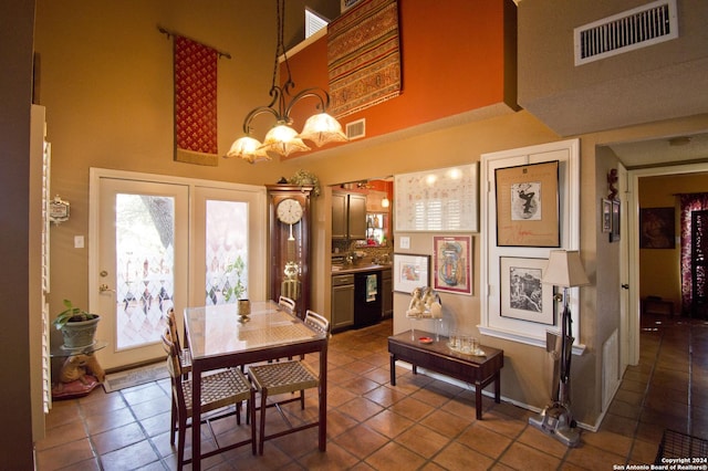 dining area featuring dark tile patterned floors, a towering ceiling, and an inviting chandelier