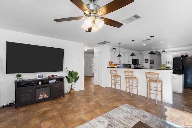 living room with ceiling fan and dark tile patterned flooring