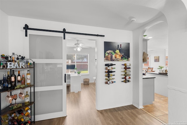 interior space with light wood-type flooring, ceiling fan, and a barn door