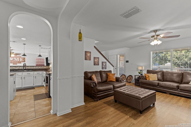 living room with ceiling fan, light hardwood / wood-style flooring, and sink