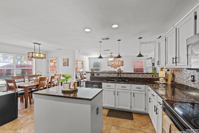 kitchen featuring pendant lighting, dark stone counters, white cabinets, sink, and a kitchen island