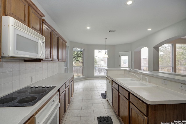 kitchen featuring decorative backsplash, white appliances, sink, pendant lighting, and light tile patterned flooring