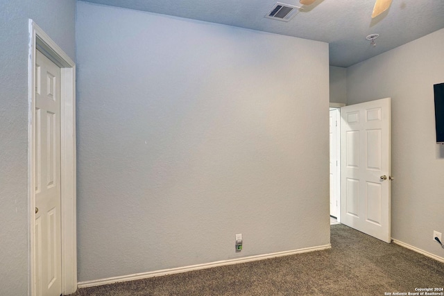 empty room featuring ceiling fan, dark carpet, and a textured ceiling