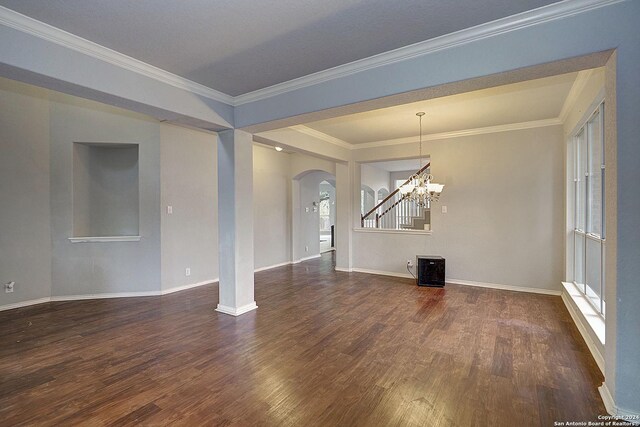 unfurnished room featuring plenty of natural light, ornamental molding, dark wood-type flooring, and an inviting chandelier