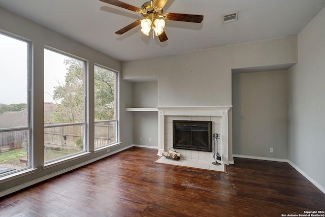 unfurnished living room with a tile fireplace, a wealth of natural light, and dark wood-type flooring