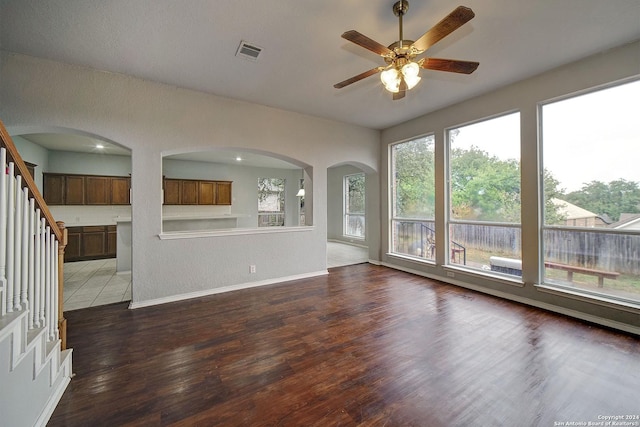 unfurnished living room with ceiling fan and dark wood-type flooring