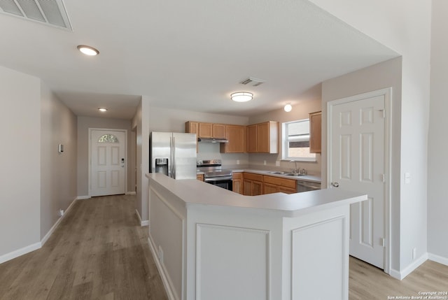 kitchen with sink, a center island, light hardwood / wood-style floors, light brown cabinetry, and appliances with stainless steel finishes