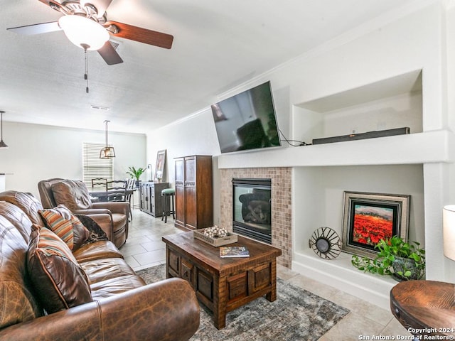 living room with a tile fireplace, ceiling fan, and light tile patterned floors