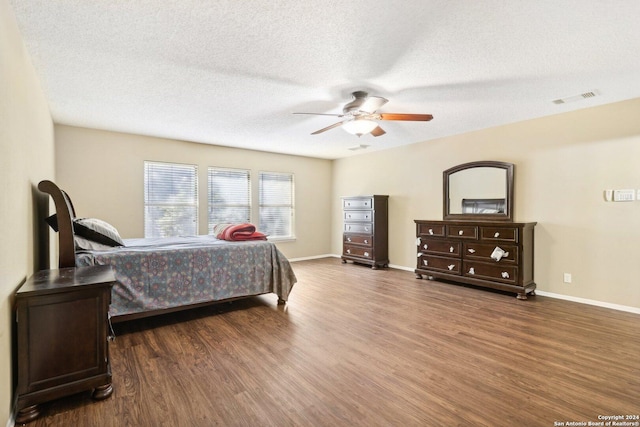 bedroom with a textured ceiling, dark hardwood / wood-style floors, and ceiling fan