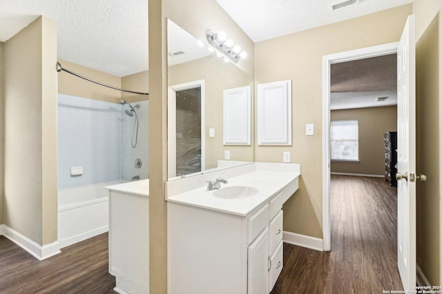 bathroom with hardwood / wood-style flooring, vanity, a textured ceiling, and tiled shower / bath