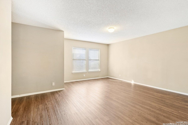 empty room with dark hardwood / wood-style flooring and a textured ceiling