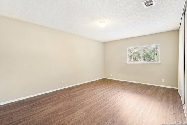 unfurnished room with dark hardwood / wood-style flooring and a textured ceiling