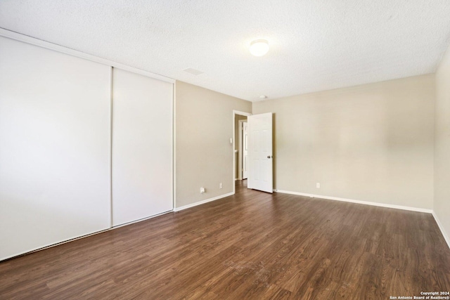 spare room featuring dark wood-type flooring and a textured ceiling