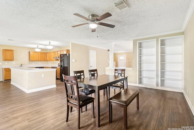 dining room featuring decorative columns, ceiling fan, light hardwood / wood-style flooring, and a textured ceiling