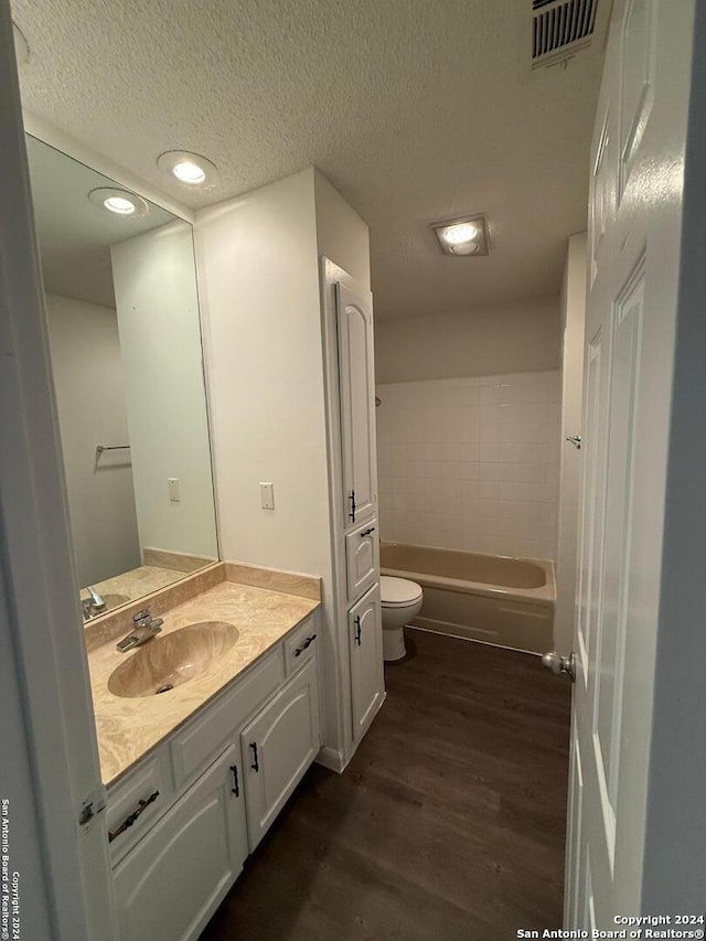 bathroom with hardwood / wood-style floors, vanity, toilet, and a textured ceiling