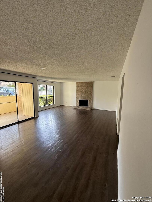 unfurnished living room with a large fireplace, wood-type flooring, and a textured ceiling