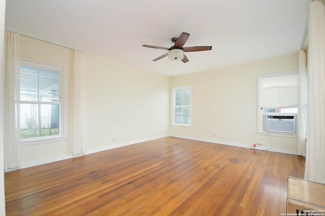 unfurnished room with ceiling fan, plenty of natural light, cooling unit, and wood-type flooring