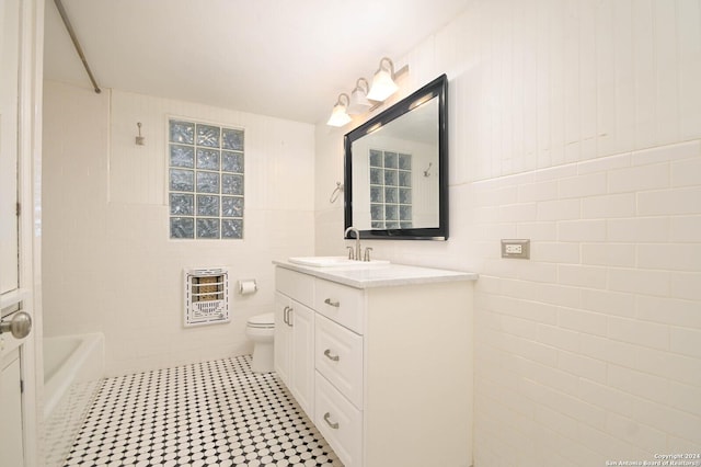 bathroom with vanity, a bathtub, toilet, tile walls, and heating unit