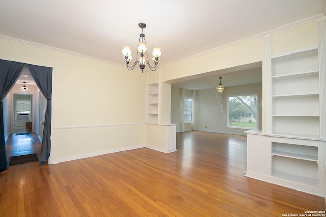 empty room with crown molding, a notable chandelier, and hardwood / wood-style flooring