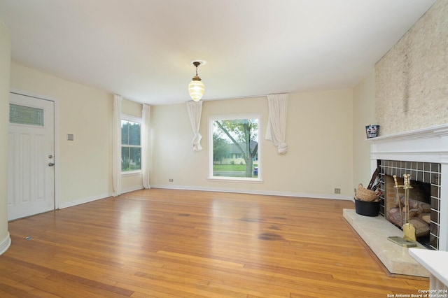 unfurnished living room featuring wood-type flooring and a large fireplace